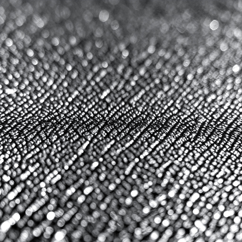 Black-and-white photograph of a textured studio surface, dense pattern of fine grooves and bright reflective edges